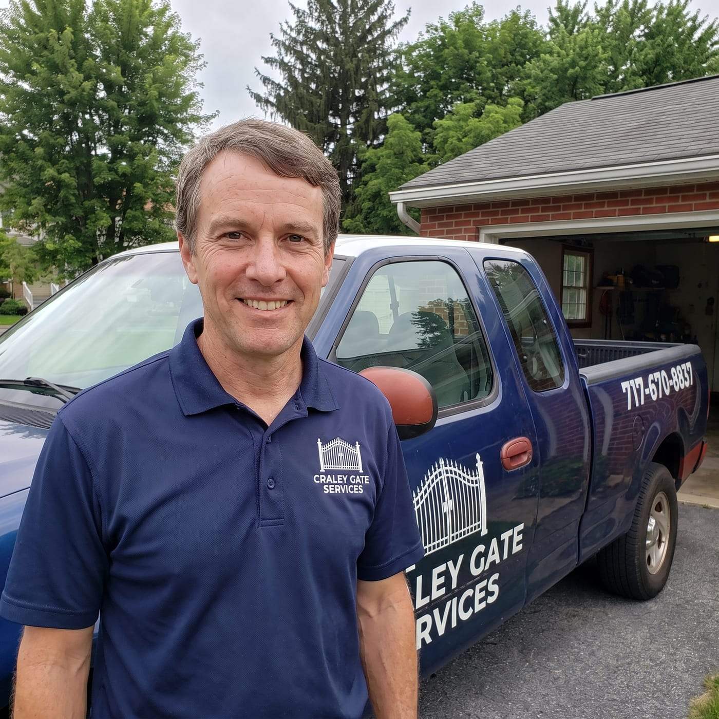 Konner Larson, manager of Craley Gate Services, smiling in a navy polo shirt with the company gate logo, standing in front of the lettered service truck